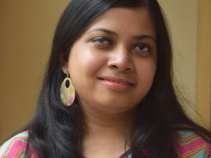 Arundhati Nath is a full-time, visually impaired freelance journalist, personal essayist, translator and children’s author from Guwahati in Northeast India. Pic: a smiling Indian woman with straight black hair and a colorful modern top.