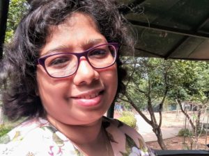 Indian journalist Swati Sanyal Tarafdar, a smiling woman with curling dark hair to her jawline, wearing a floral topic and standing outside in a sunny garden