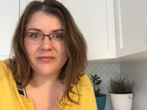 Journalist Vanessa Chiasson, a white Canadian author with brow, straight hair to her collarbones and stylish glasses. She's wearing a canary-colored shirt and is posed in a kitchen with plants and white cupboards