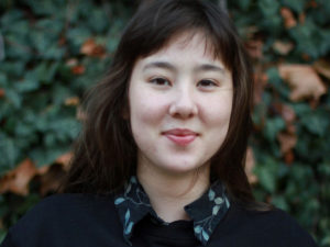 Korean-American chef and writer Hanna T. Gregor, a smiling woman with black bangs and long hair, a floral button-down shirt and sweater